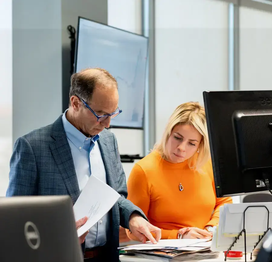 Two coworkers reviewing documents together at a desk in an office