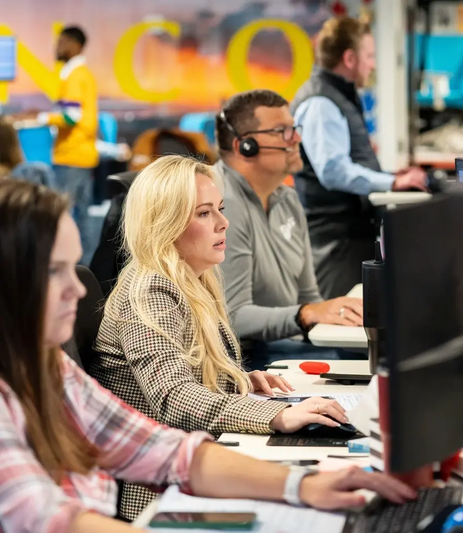 Team members wearing headsets working at computers in an office
