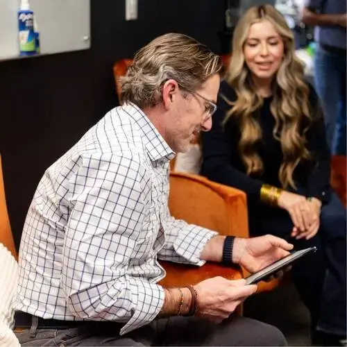 Two coworkers sitting and discussing information on a tablet in an office lounge