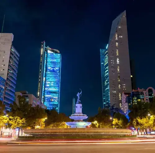 Diana the Huntress fountain at night on Paseo de la Reforma in Mexico City with illuminated skyscrapers