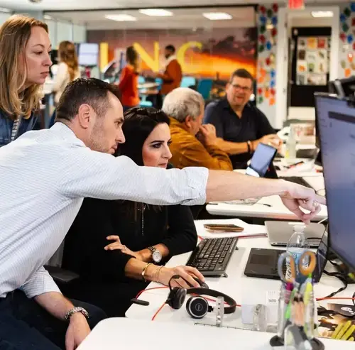 Team collaborating in an office, reviewing data on a computer screen
