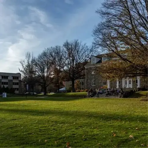 Students sitting outside on the steps of a campus building overlooking a grassy lawn