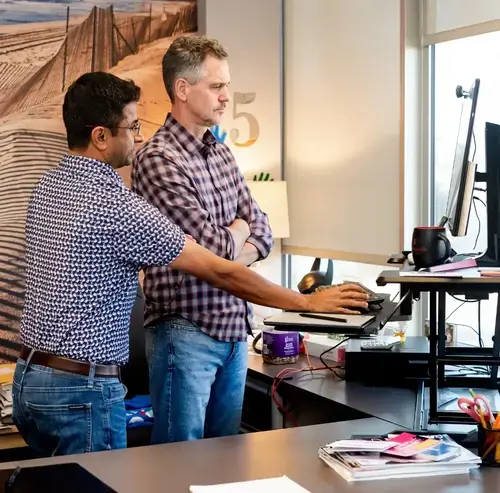 Two colleagues working together at a standing desk in an office